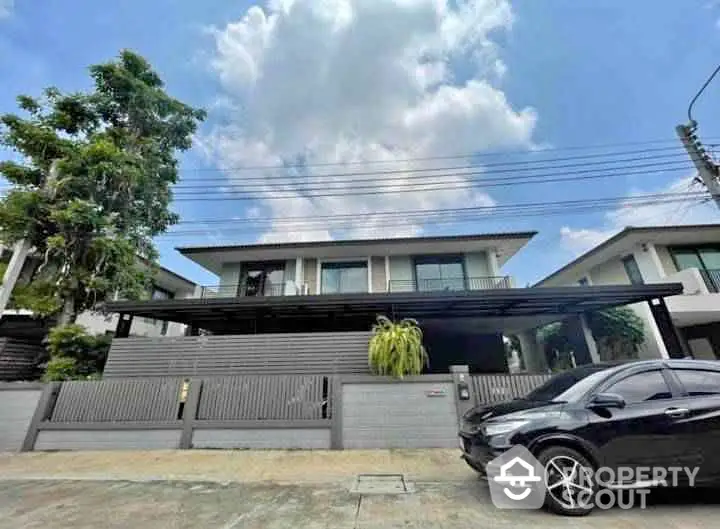 Modern two-story house with sleek design and spacious driveway in suburban neighborhood.