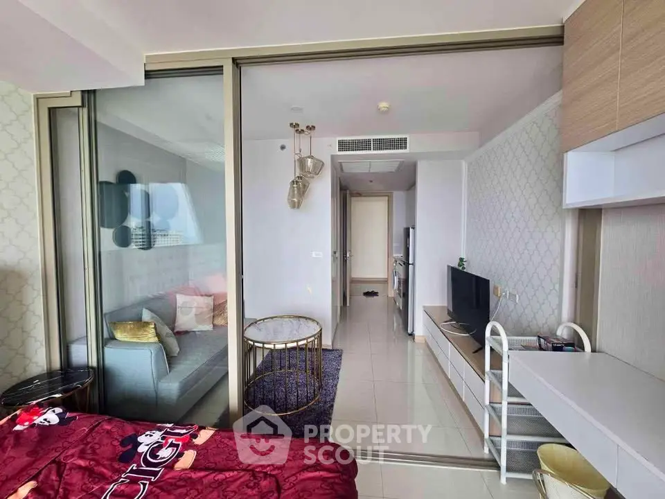 Modern apartment interior with stylish living room and cozy bedroom separated by glass doors.
