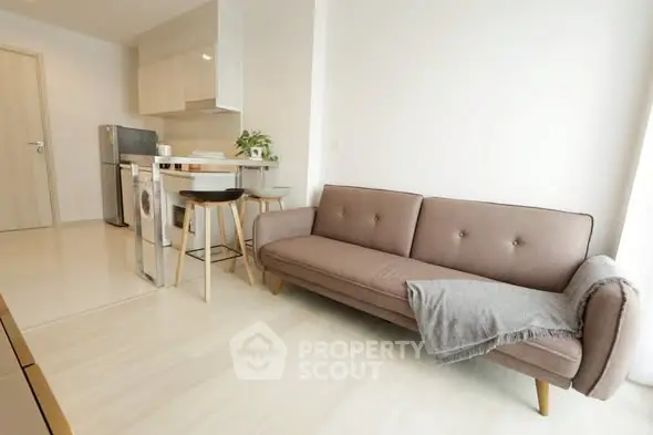Modern living room with stylish sofa and compact kitchen in open layout apartment.