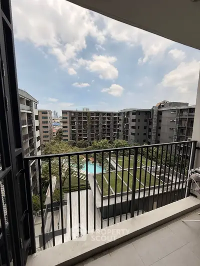 Stunning balcony view of modern apartment complex with pool and lush greenery.