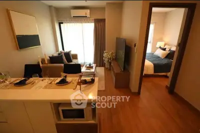 Modern open-plan living room with cozy bedroom view, stylish decor, and natural light.