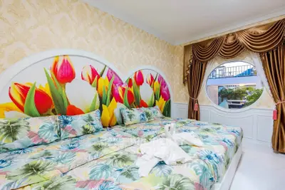 Vibrant bedroom with floral decor and large window offering scenic view