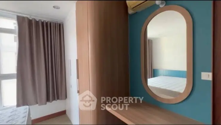 Cozy bedroom with modern wooden wardrobe and stylish oval mirror