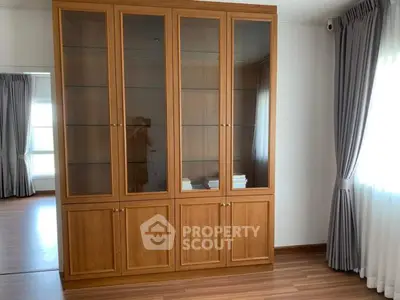 Spacious room with elegant wooden cabinet and large windows for natural light
