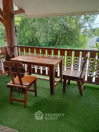Charming wooden balcony with lush garden view, perfect for relaxation and outdoor dining.
