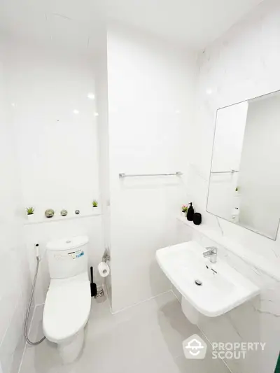 Pristine white bathroom with modern fixtures, wall-mounted sink, and eco-friendly toilet, accented with green plants for a fresh, clean look.