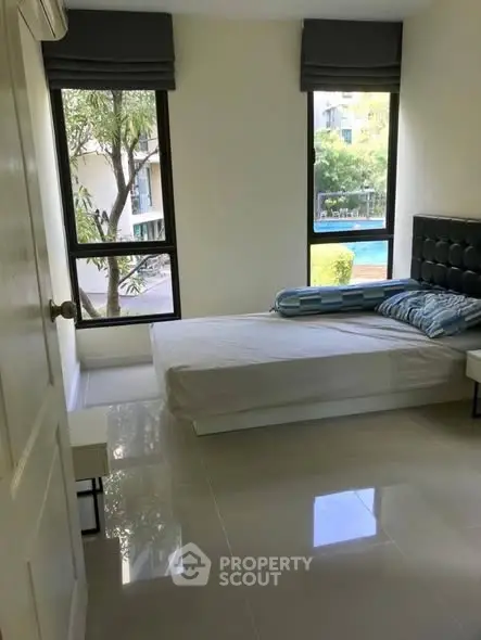 Bright bedroom with large windows and pool view in modern apartment
