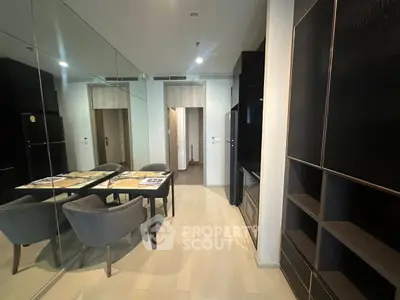 Modern dining area with sleek black furniture and mirrored wall in a stylish apartment.