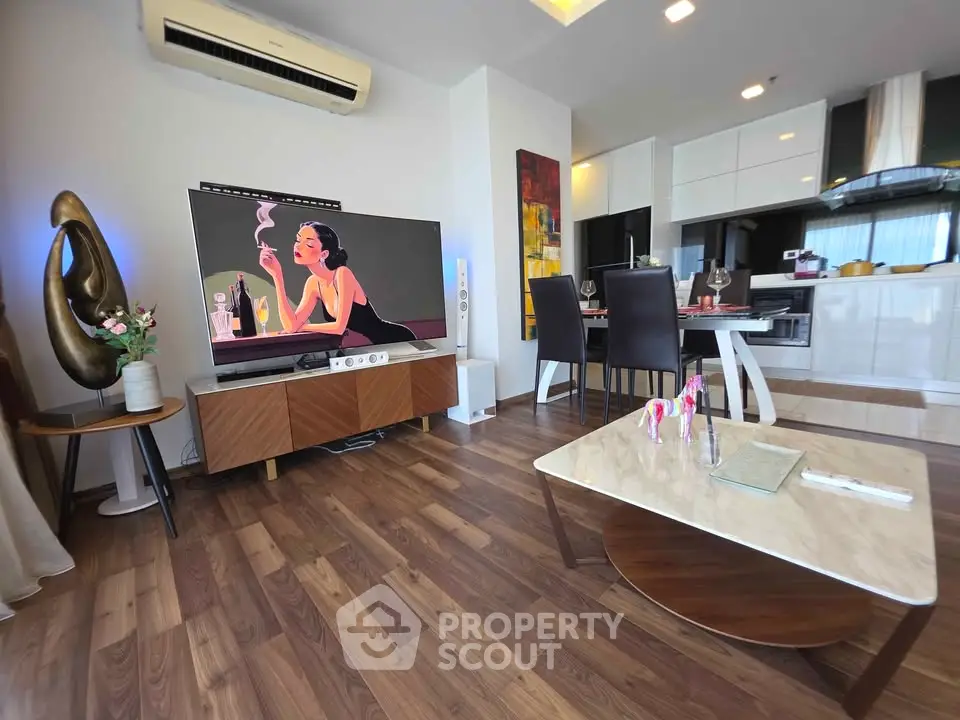 Modern living room with stylish decor and open kitchen layout, featuring sleek furniture and wooden flooring.