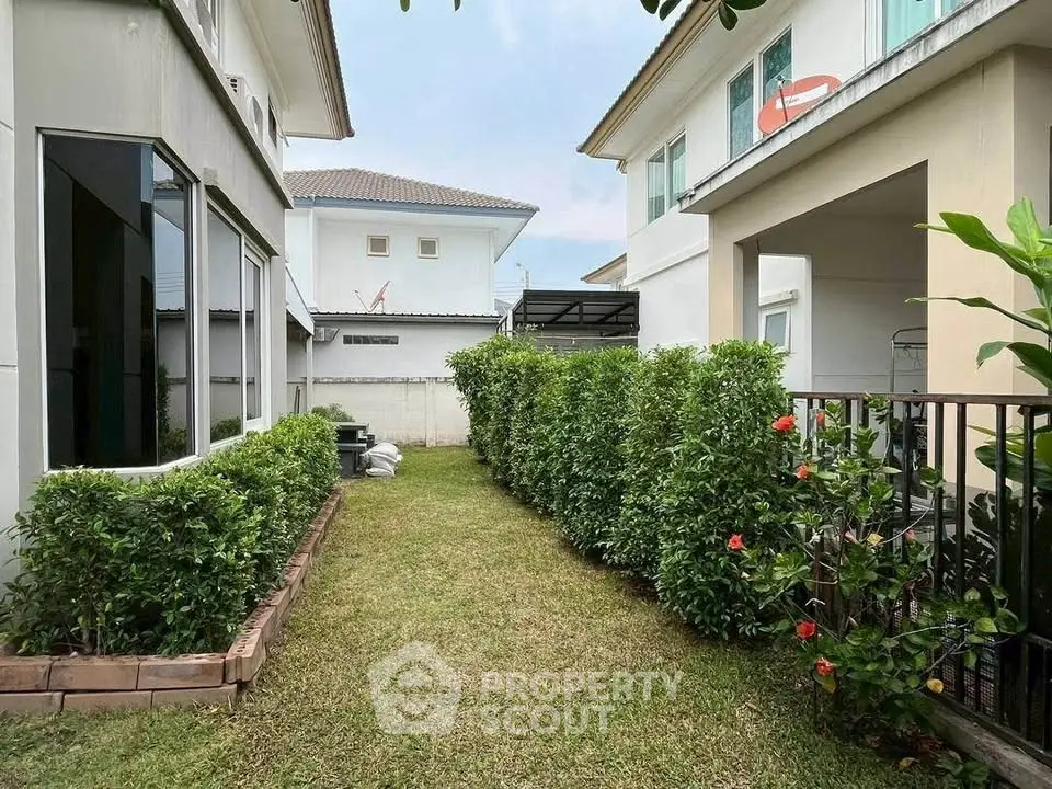 Charming garden view between modern homes with lush greenery and well-maintained hedges.