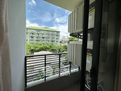 Charming balcony view with lush greenery and modern building backdrop, perfect for urban living.