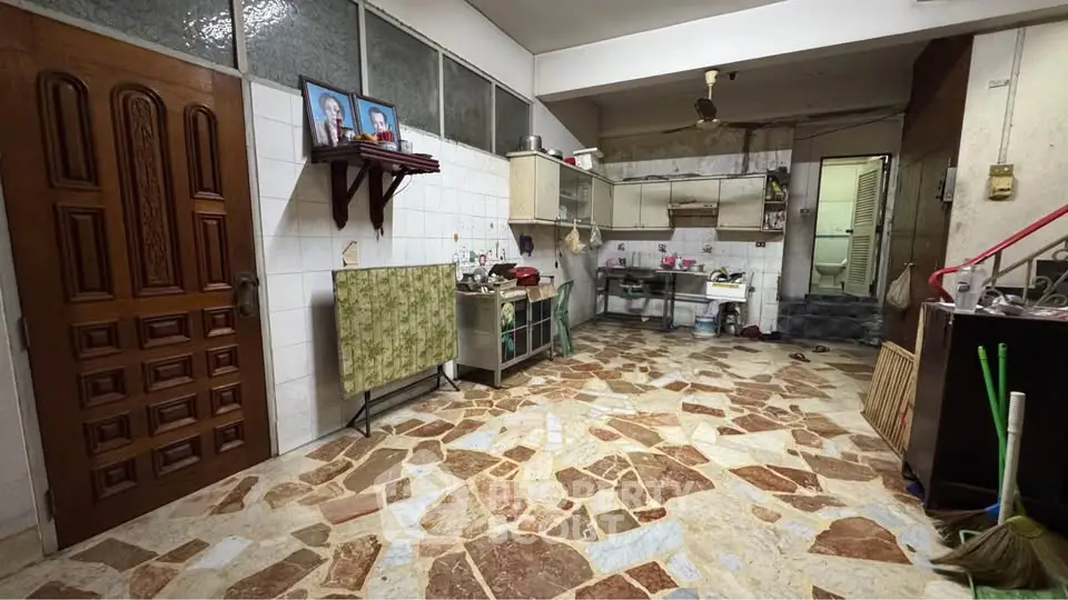 Spacious kitchen with unique stone flooring and wooden door, featuring open layout and ample storage space.