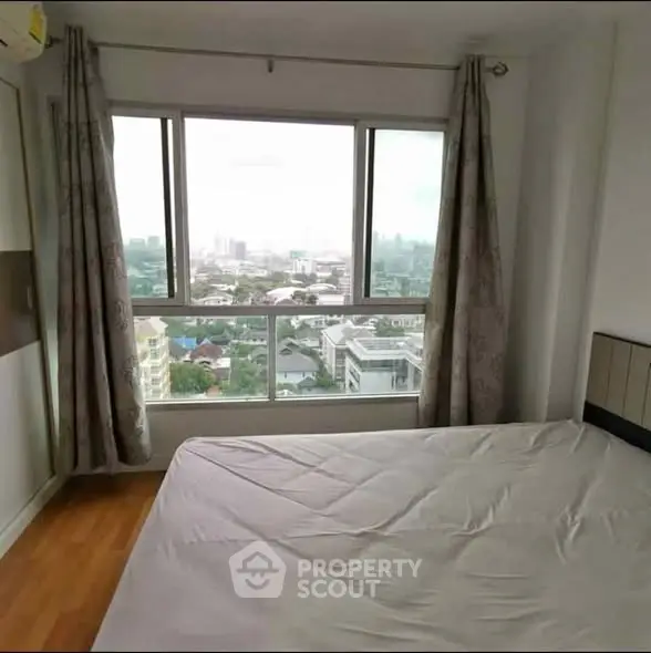 Spacious bedroom with large window offering stunning city views