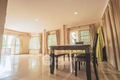 Spacious living room with large windows and elegant curtains, perfect for natural light and comfort.