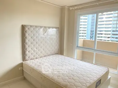 Spacious bedroom with large window and modern bed in urban apartment