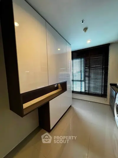 Modern laundry room with sleek cabinetry and washing machine in stylish apartment.