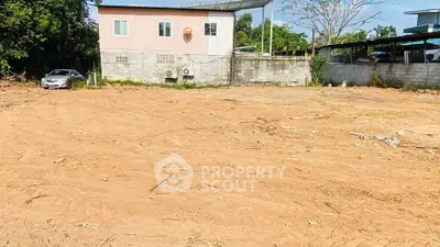 Spacious empty plot of land with potential for development, featuring a small building and surrounding greenery.