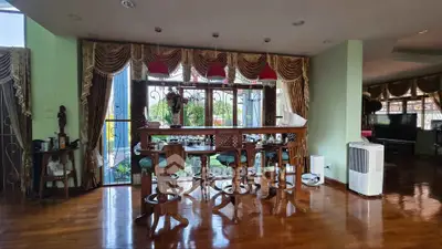 Elegant living room with wooden floors, bar counter, and large windows offering scenic views.