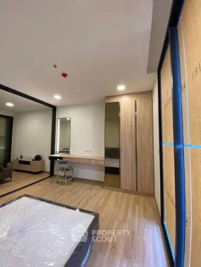 Modern bedroom with wooden flooring and large mirrored wardrobe
