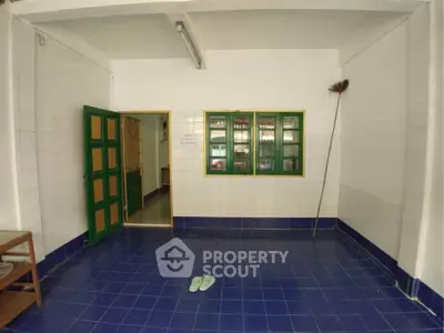 Spacious tiled room with green accents and open doorway, ideal for versatile use.