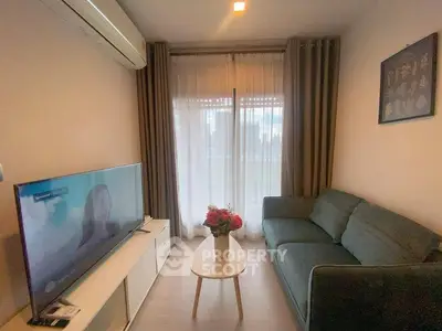 Cozy living room with modern sofa, TV, and natural light from large window.