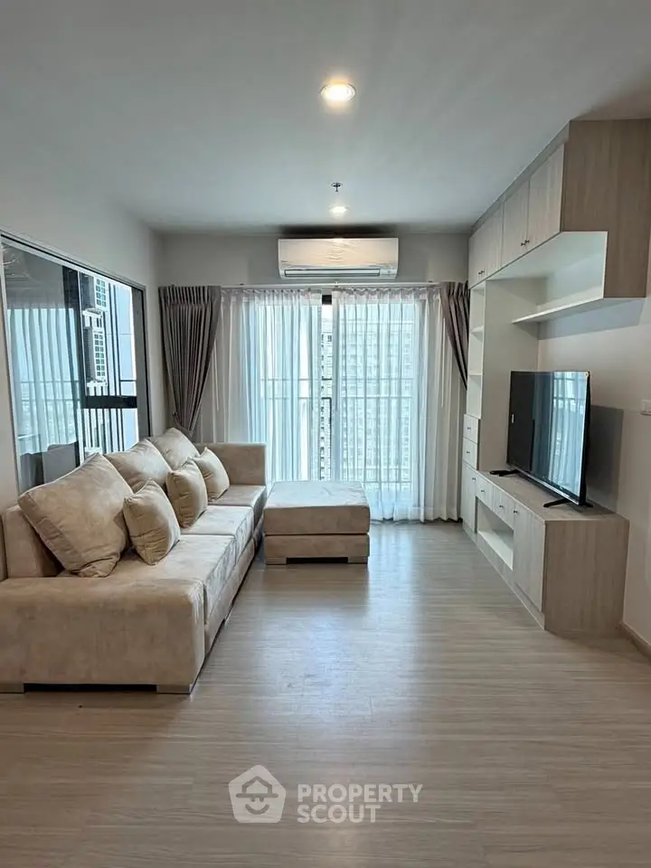 Spacious modern living room with large windows and stylish furniture in a high-rise apartment.
