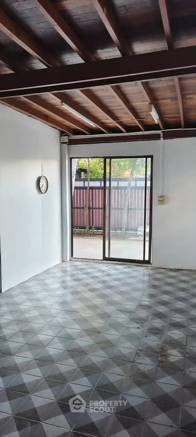 Spacious room with tiled floor and sliding glass door leading to outdoor area.