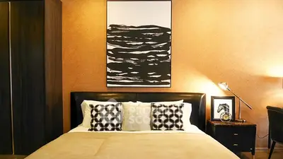 Luxurious bedroom with stylish decor and modern artwork above bed.