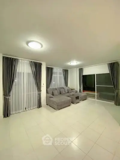 Spacious living room with modern gray sofa and elegant curtains