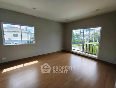 Spacious empty room with large windows and balcony overlooking greenery, perfect for customization.