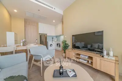 Modern living room with open kitchen, featuring stylish furniture and appliances.