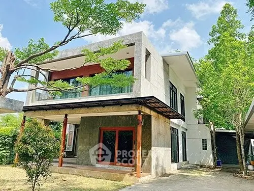 Modern two-story house with large windows and lush greenery