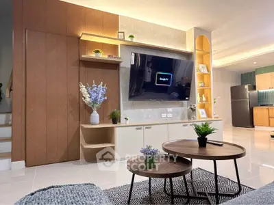 Modern living room with stylish decor, wall-mounted TV, and open kitchen layout.