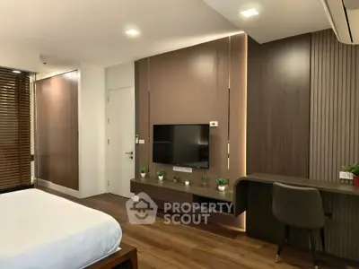 Modern bedroom with sleek wooden paneling and built-in TV, featuring a cozy workspace and elegant decor.