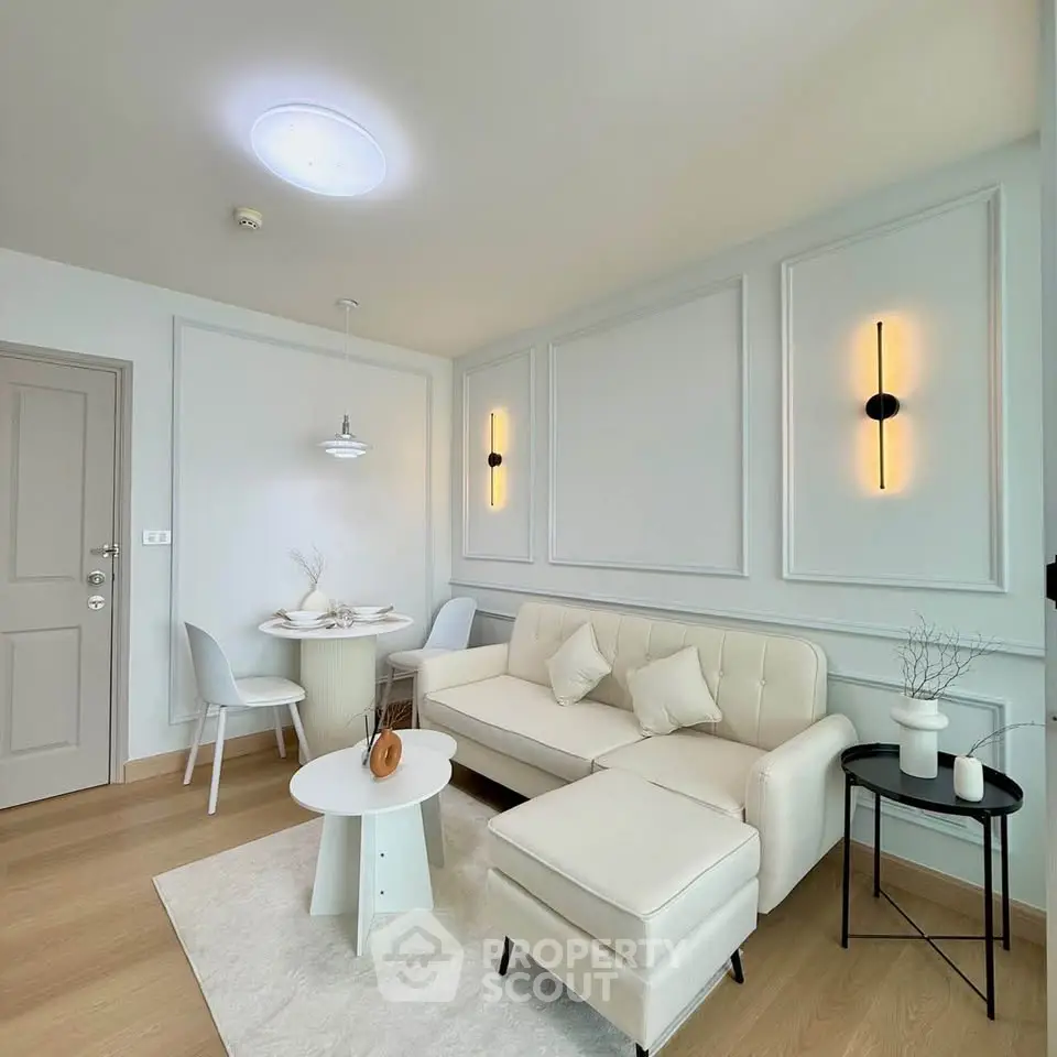 Modern living room with elegant decor, featuring a cozy white sofa, stylish lighting, and a chic dining area.