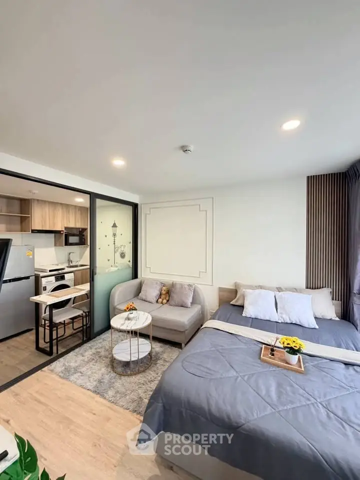 Modern studio apartment with cozy bed and compact kitchen area