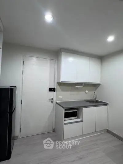 Modern compact kitchen with sleek cabinetry and built-in appliances in a minimalist apartment.