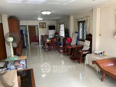Spacious living room with tiled flooring and wooden furniture, featuring large windows for natural light.