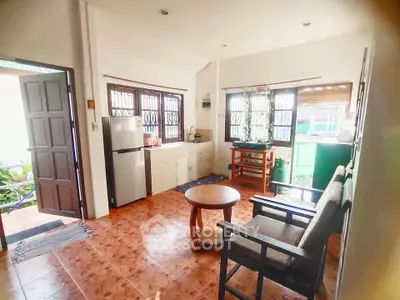 Charming open-layout living room with kitchen, featuring natural light and cozy furnishings.