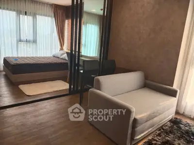 Modern apartment with cozy living area and stylish bedroom separated by glass partition.