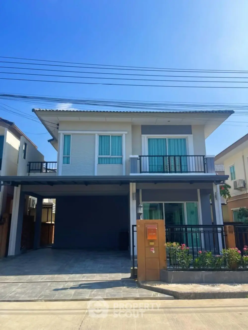 Modern two-story house with balcony and driveway in suburban neighborhood.