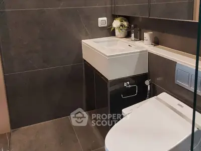 Modern bathroom with sleek fixtures and dark tile design.