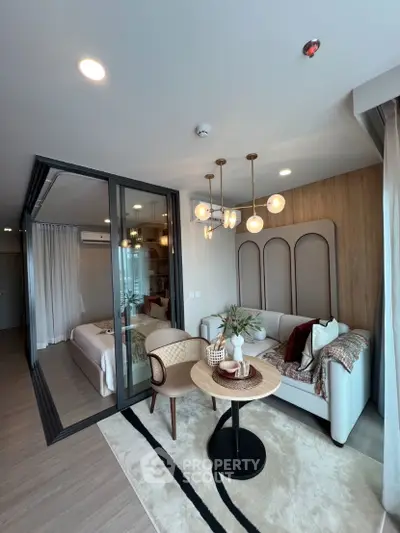 Modern living room with stylish decor and glass partition leading to bedroom