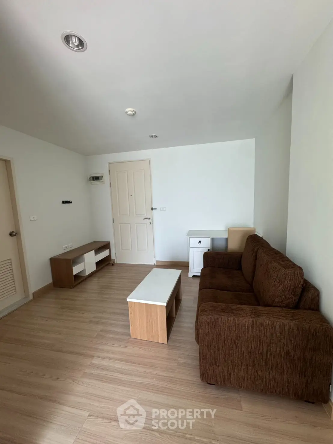 Spacious living room with modern furniture and wooden flooring in a cozy apartment.