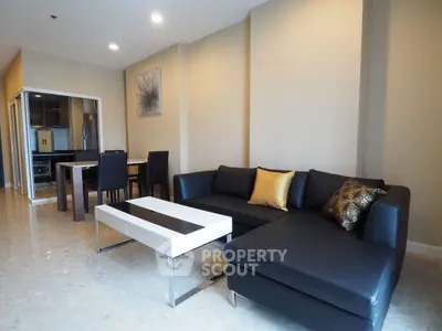 Modern living room with sleek black sofa and stylish dining area in open layout.
