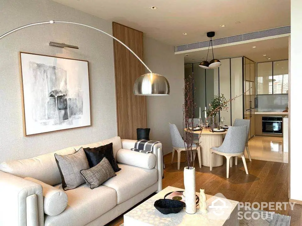 Modern living room with elegant decor and open kitchen layout, featuring stylish furniture and contemporary lighting.