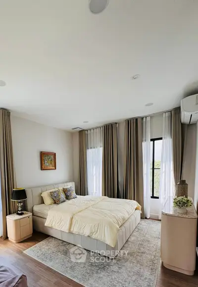Elegant bedroom with modern decor, large windows, and cozy bedding in a stylish home.