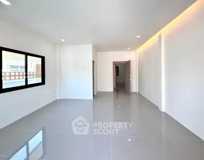 Spacious modern living room with sleek tile flooring and large window, perfect for natural light.