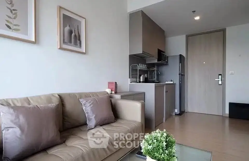 Modern living room with cozy sofa and compact kitchen in open layout apartment.