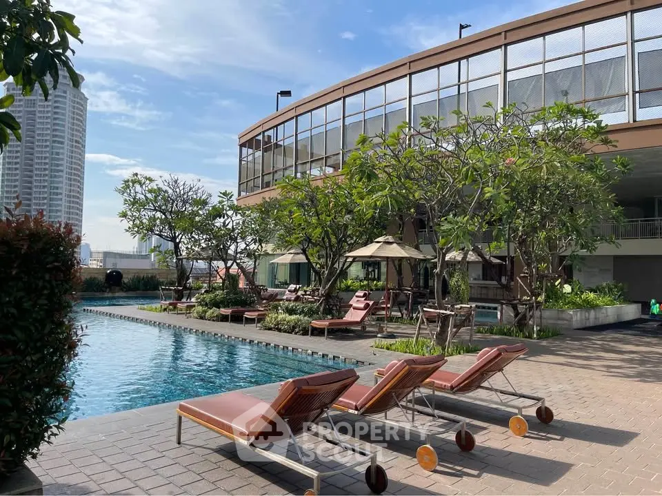 Luxurious rooftop pool area with sun loungers and lush greenery in a modern building.